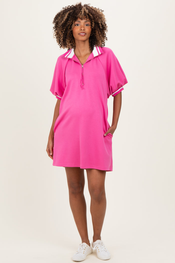 woman wearing a bright pink maternity polo dress with a collar and loose fit, showing her baby bump
