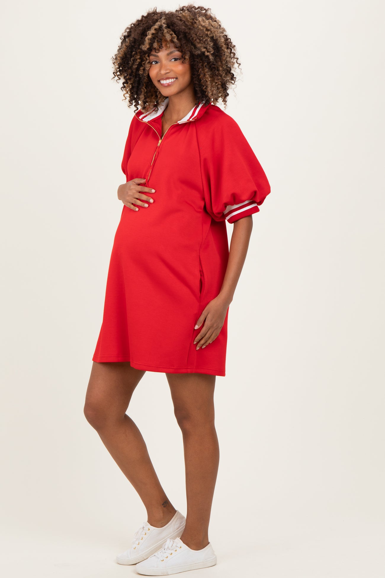 woman wearing a red short sleeve maternity dress with a zip collar and side pockets, showcasing her baby bump