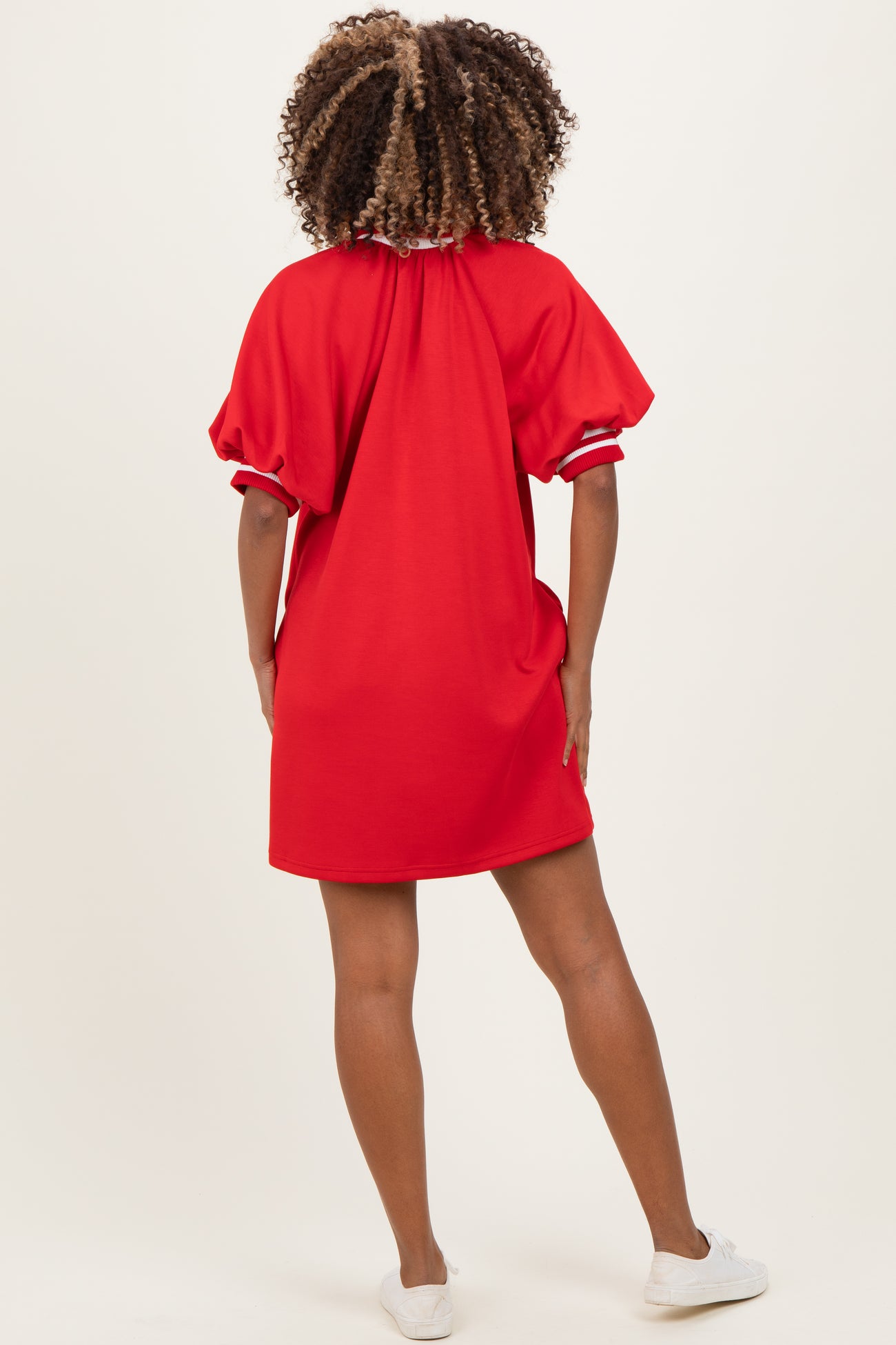 woman wearing a red maternity dress with puff sleeves and a relaxed fit, showing a casual and comfortable style