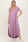 woman wearing a lavender short sleeve maxi dress with a high-low hem and side slits, paired with white sneakers