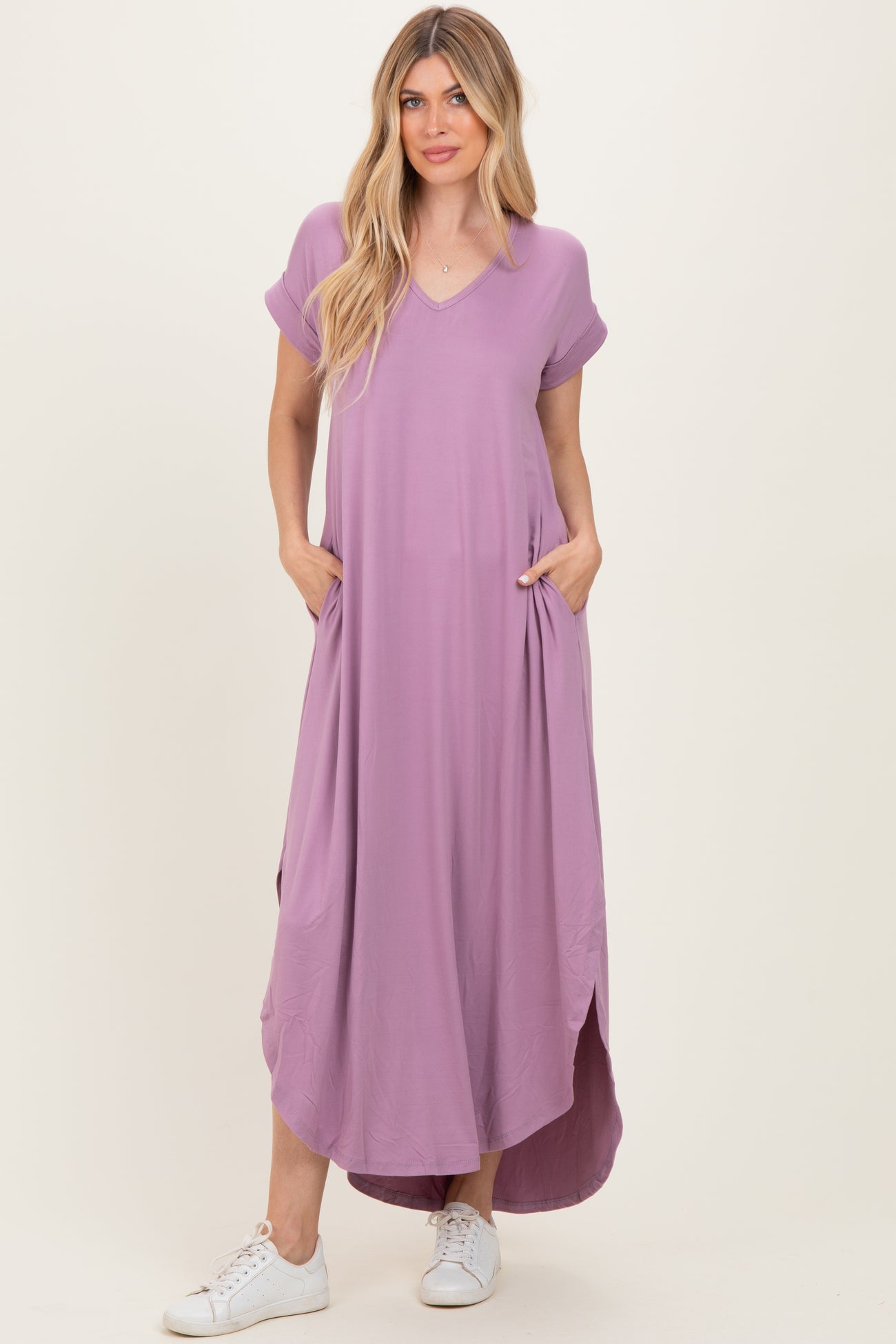 woman wearing a lavender short sleeve maxi dress with pockets and side slits, paired with white sneakers