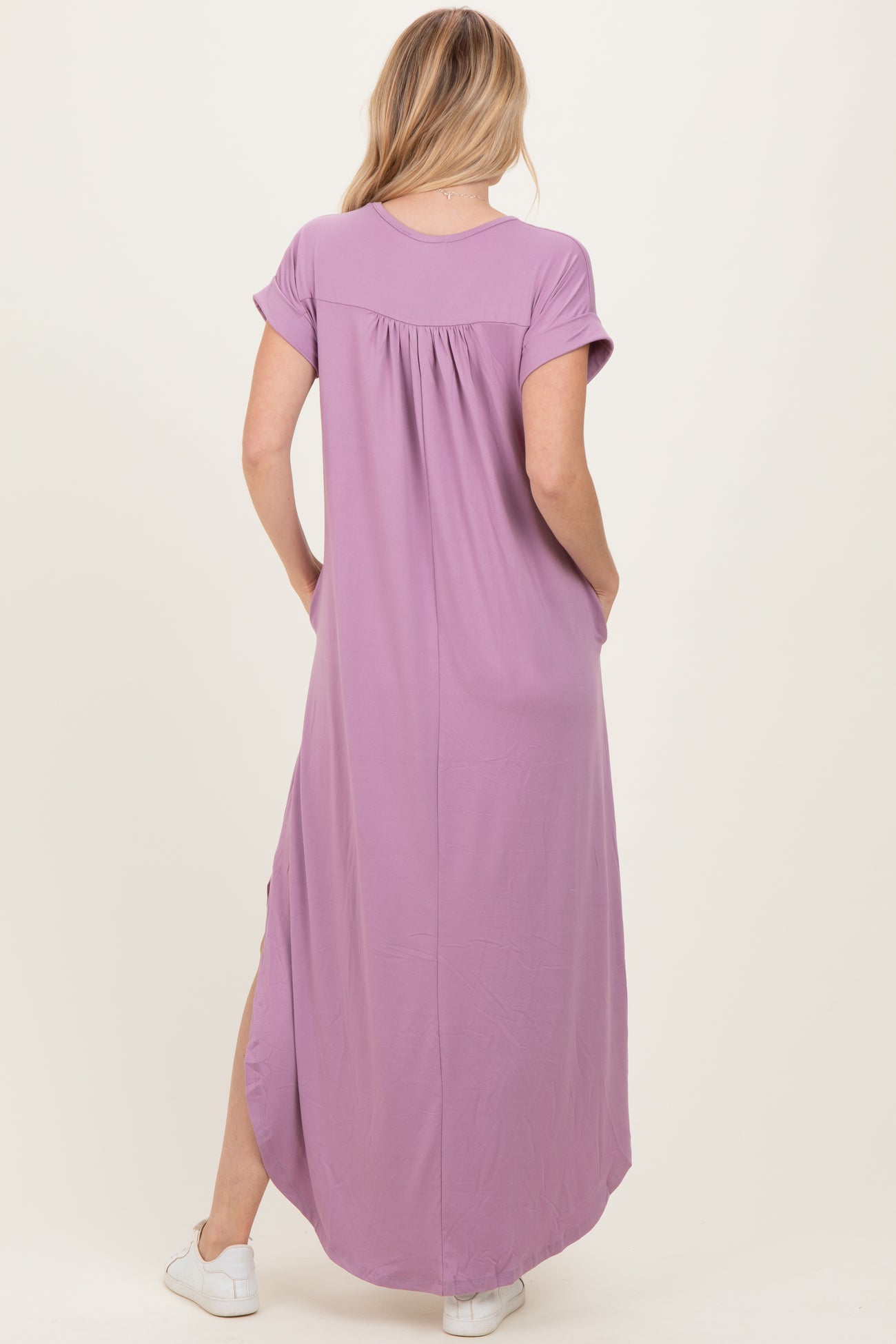 woman wearing a lavender maxi dress with short sleeves and side slits, viewed from the back