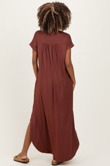 woman wearing a rust-colored maternity maxi dress with short sleeves and a pleated back design