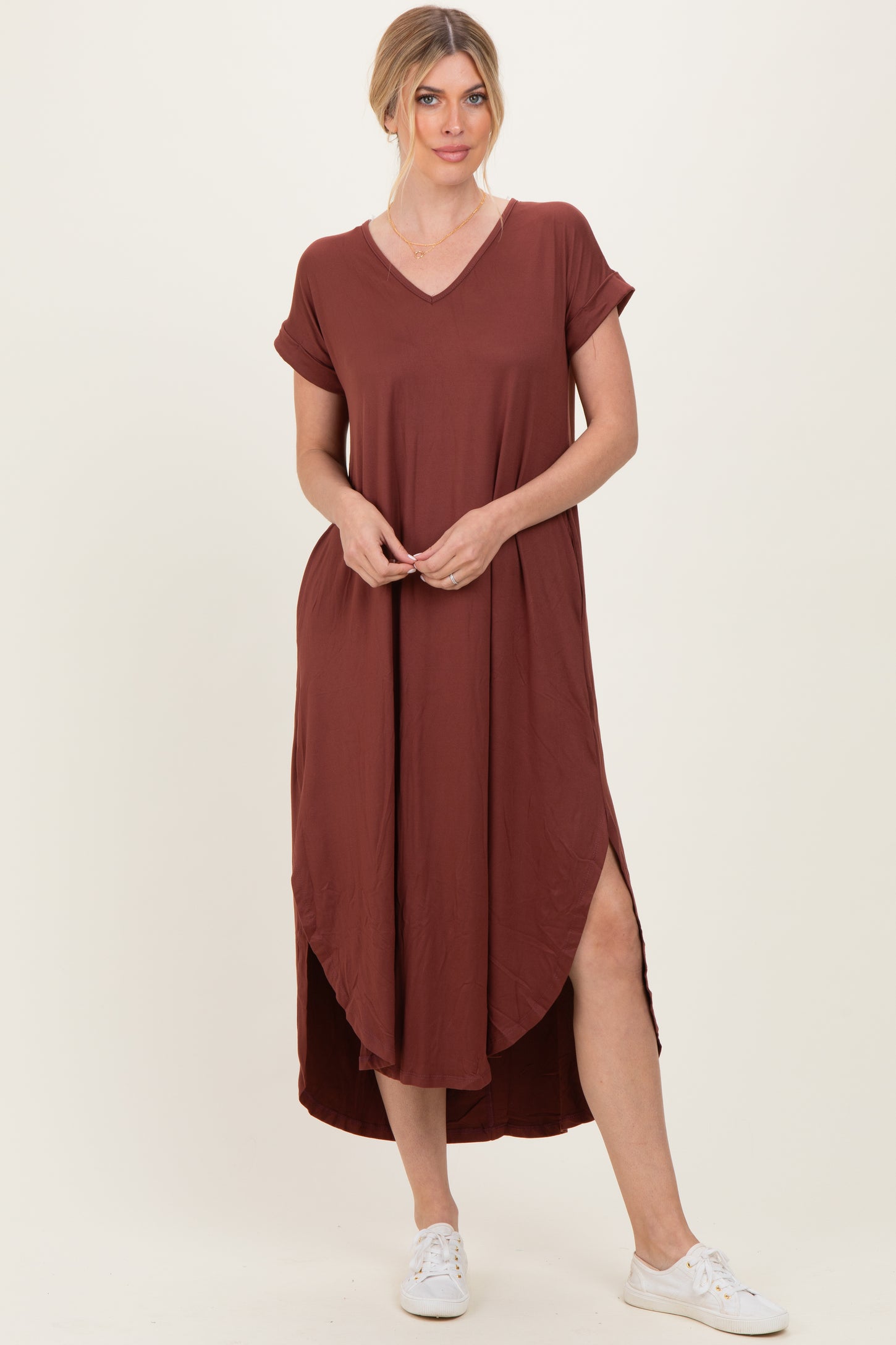 woman wearing a rust-colored short sleeve maxi dress with a v-neck and side slits