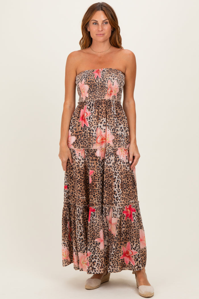 woman wearing a strapless maxi dress with a leopard print and floral design in brown and pink tones