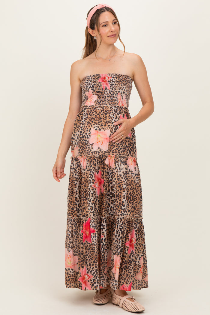 woman wearing a leopard print maternity maxi dress with floral accents and holding her baby bump