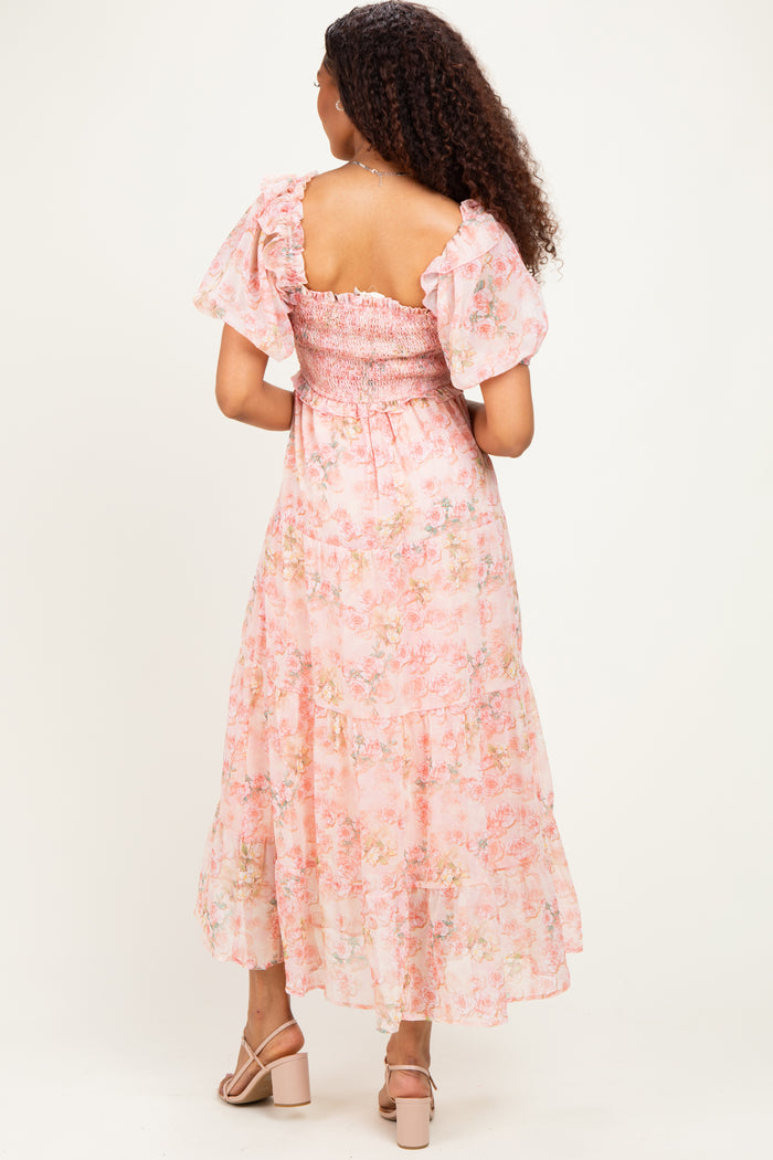 woman wearing a pink floral smocked maxi dress with ruffled sleeves and open back