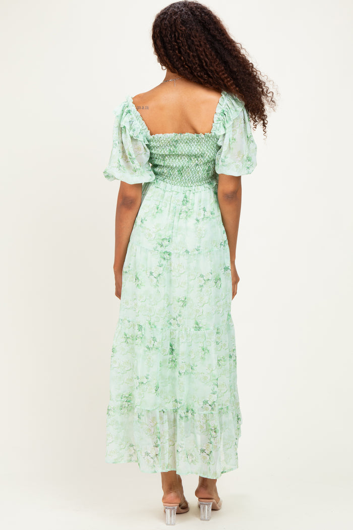 woman wearing a green floral maxi dress with short puff sleeves and a smocked bodice, viewed from the back