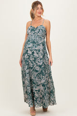 woman wearing a green floral maternity maxi dress with spaghetti straps and a visible baby bump