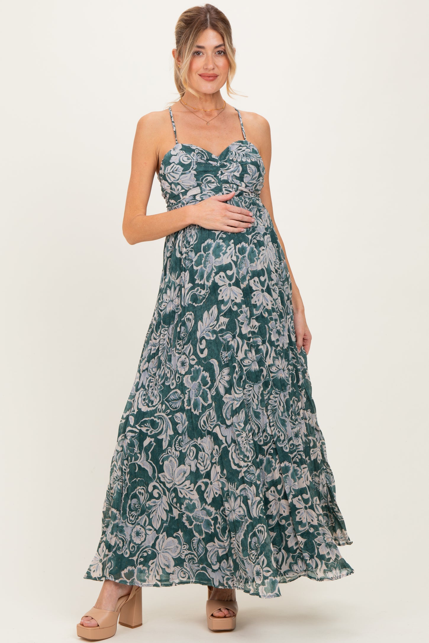 woman wearing a green floral maxi maternity dress and holding her baby bump