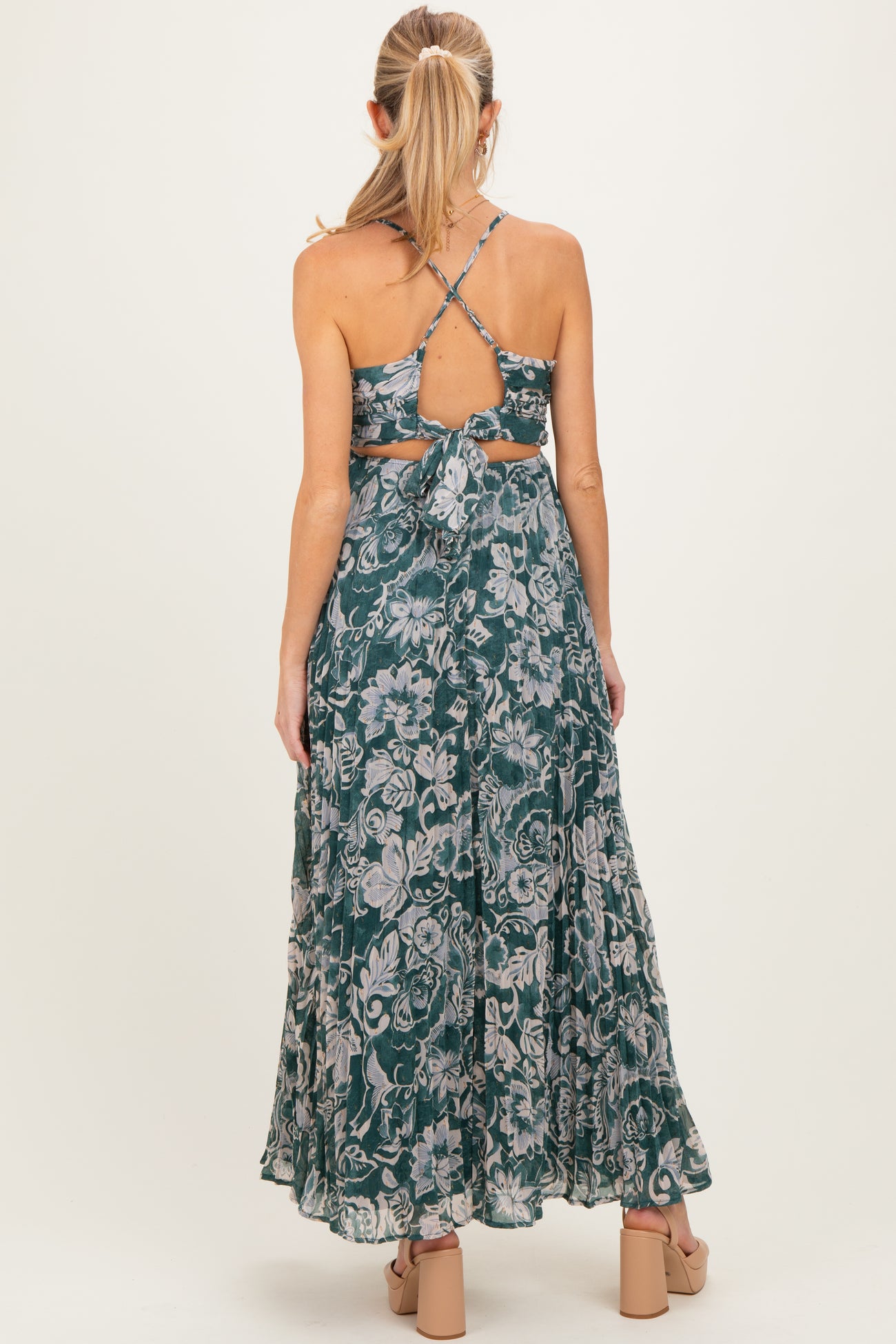 woman wearing a floral green maternity maxi dress with a strappy back and a tied waist detail