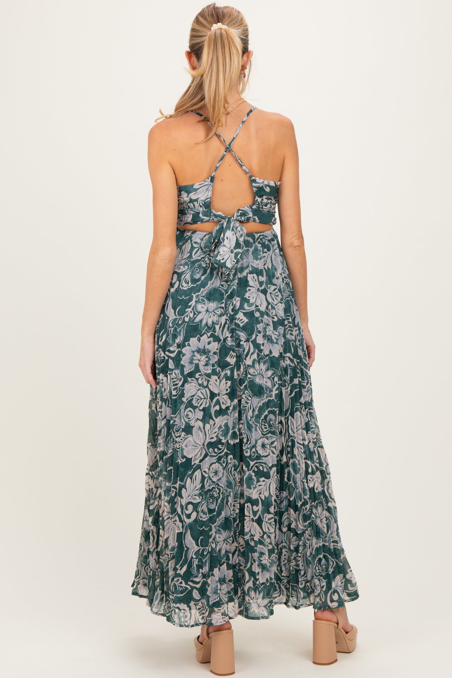 woman wearing a floral green maternity maxi dress with a strappy back and a tied waist detail