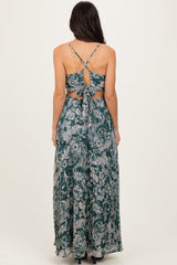 woman wearing a sleeveless green floral maxi dress with an open back and tie detail