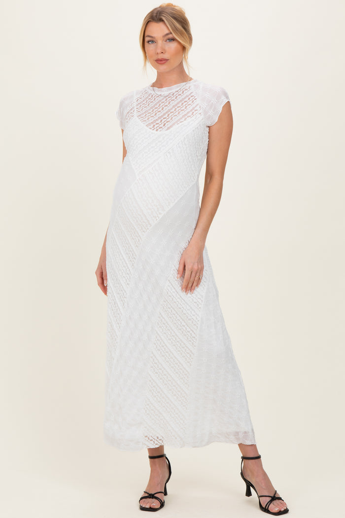 woman wearing a white lace cap sleeve maternity dress with a floor-length hem and a relaxed fit