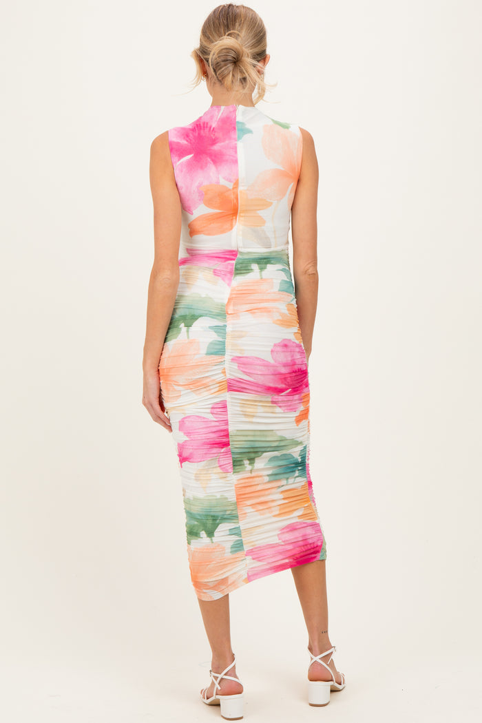 woman wearing a floral print maternity dress with a fitted silhouette and sleeveless design, showing a baby bump