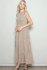 woman wearing a sleeveless floral maxi dress with a fitted bodice and tiered skirt, standing against a light background
