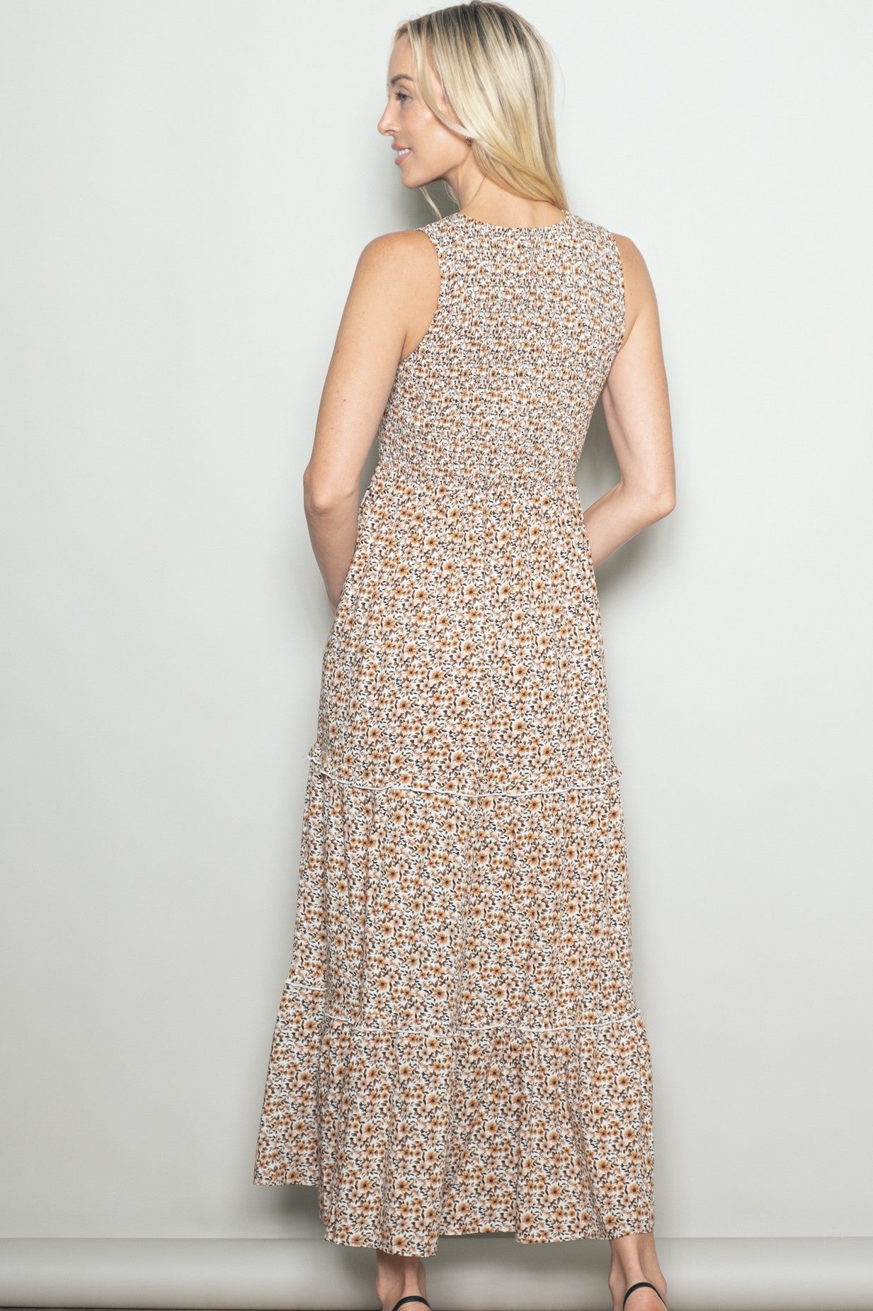 woman wearing a back view of a floral print sleeveless maxi dress with tiered ruffles