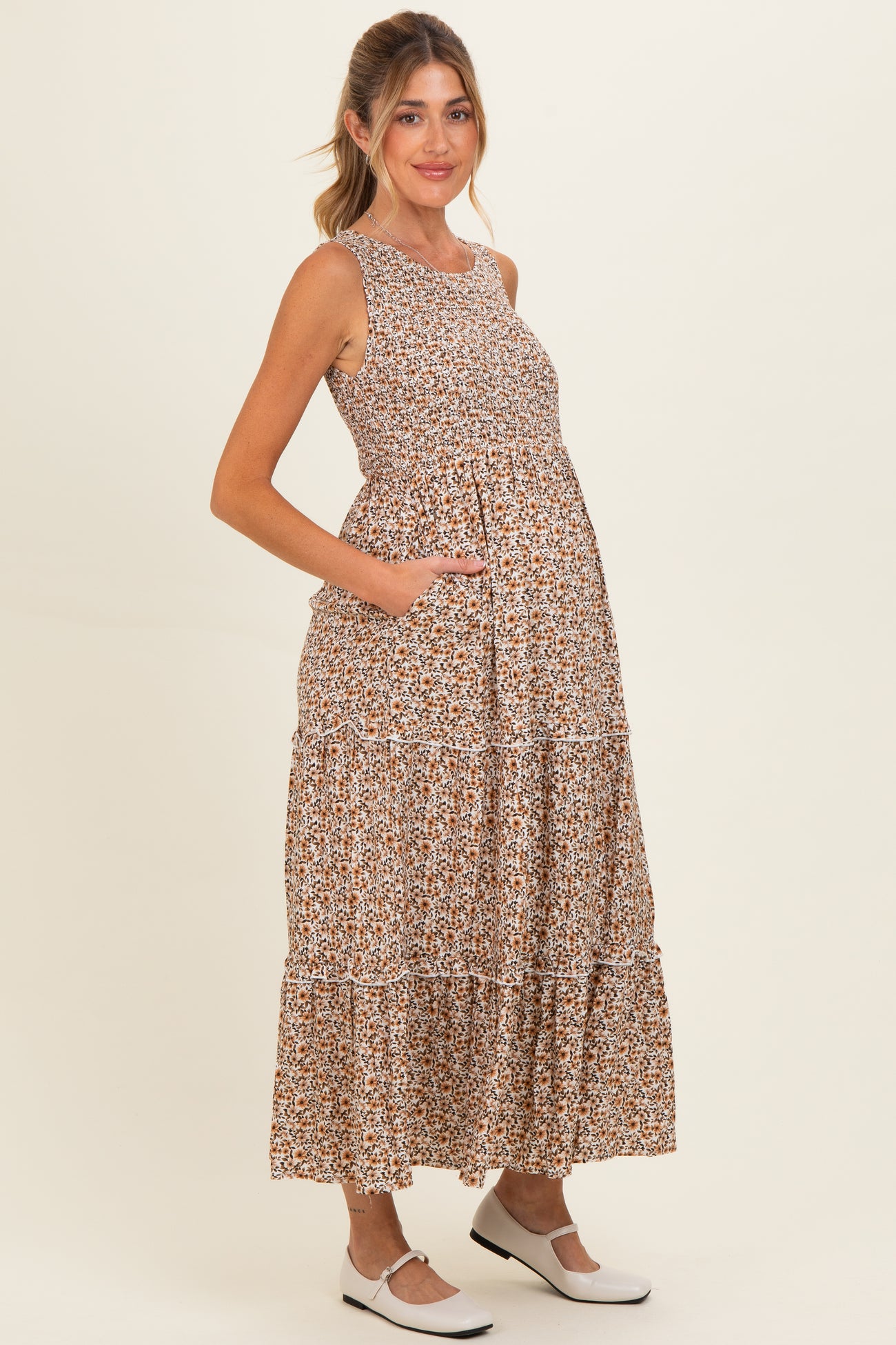woman wearing a brown floral maternity maxi dress with pockets and a baby bump visible