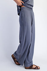 woman wearing gray wide-leg pants with an elastic waistband and side pockets, paired with brown sandals