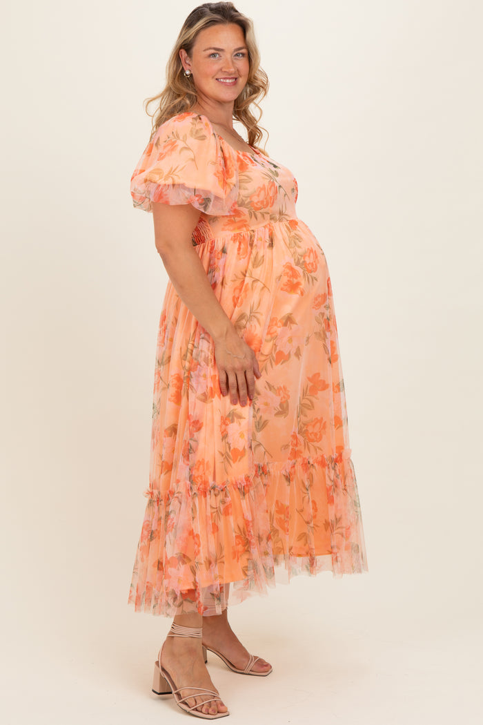 woman wearing a floral peach maternity dress with puff sleeves and ruffled hem, highlighting her baby bump