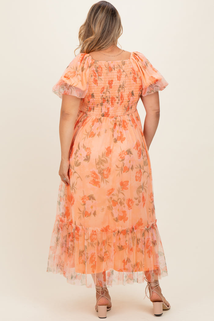 woman wearing a floral maternity plus dress in peach with puff sleeves and a tiered skirt, showing the back view