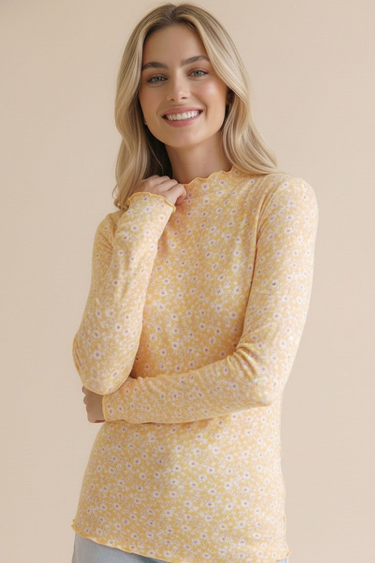 woman wearing a yellow long sleeve top with a floral pattern and a scalloped neckline