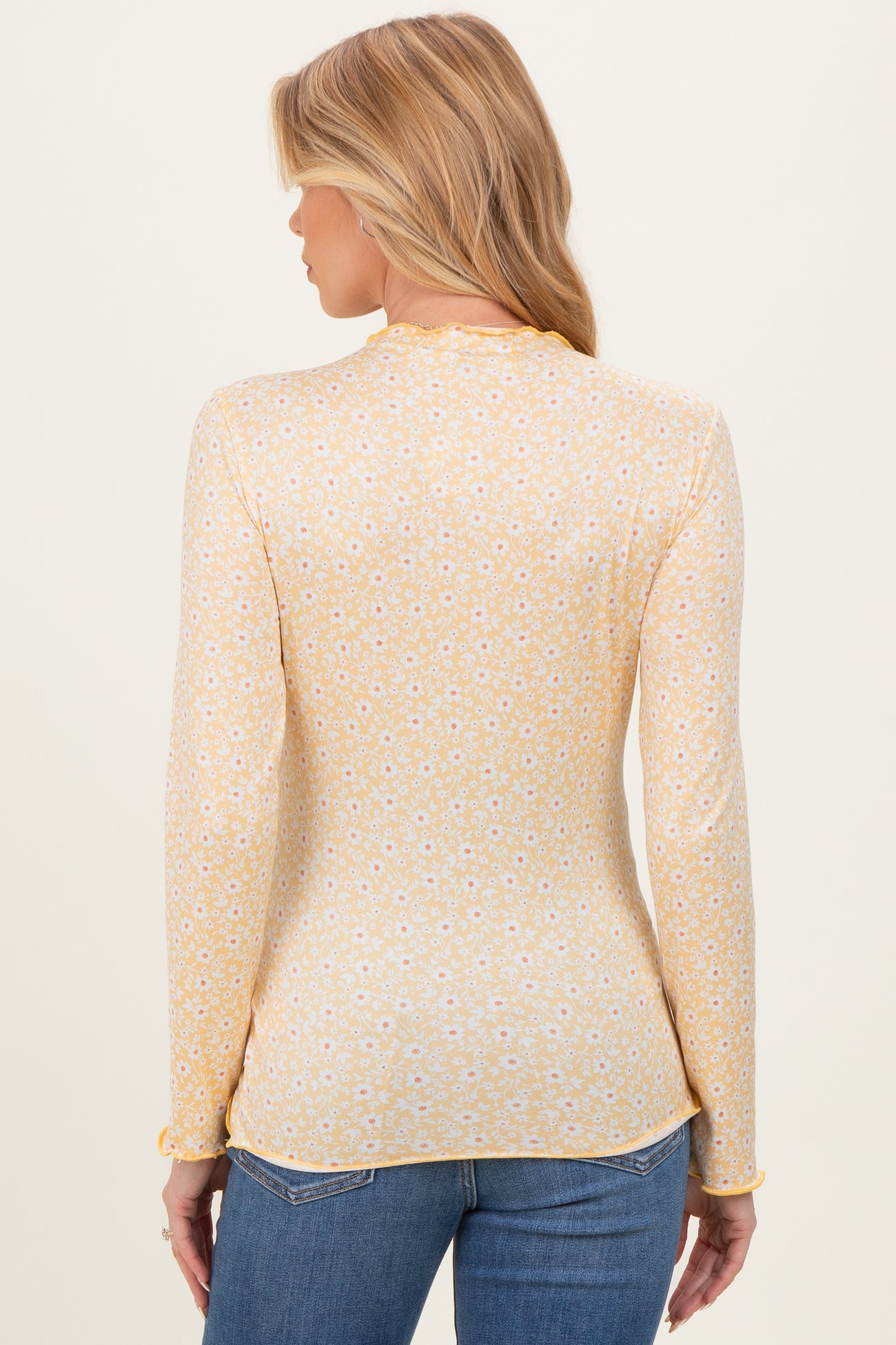 woman wearing a yellow long sleeve maternity top with a floral pattern and light fabric