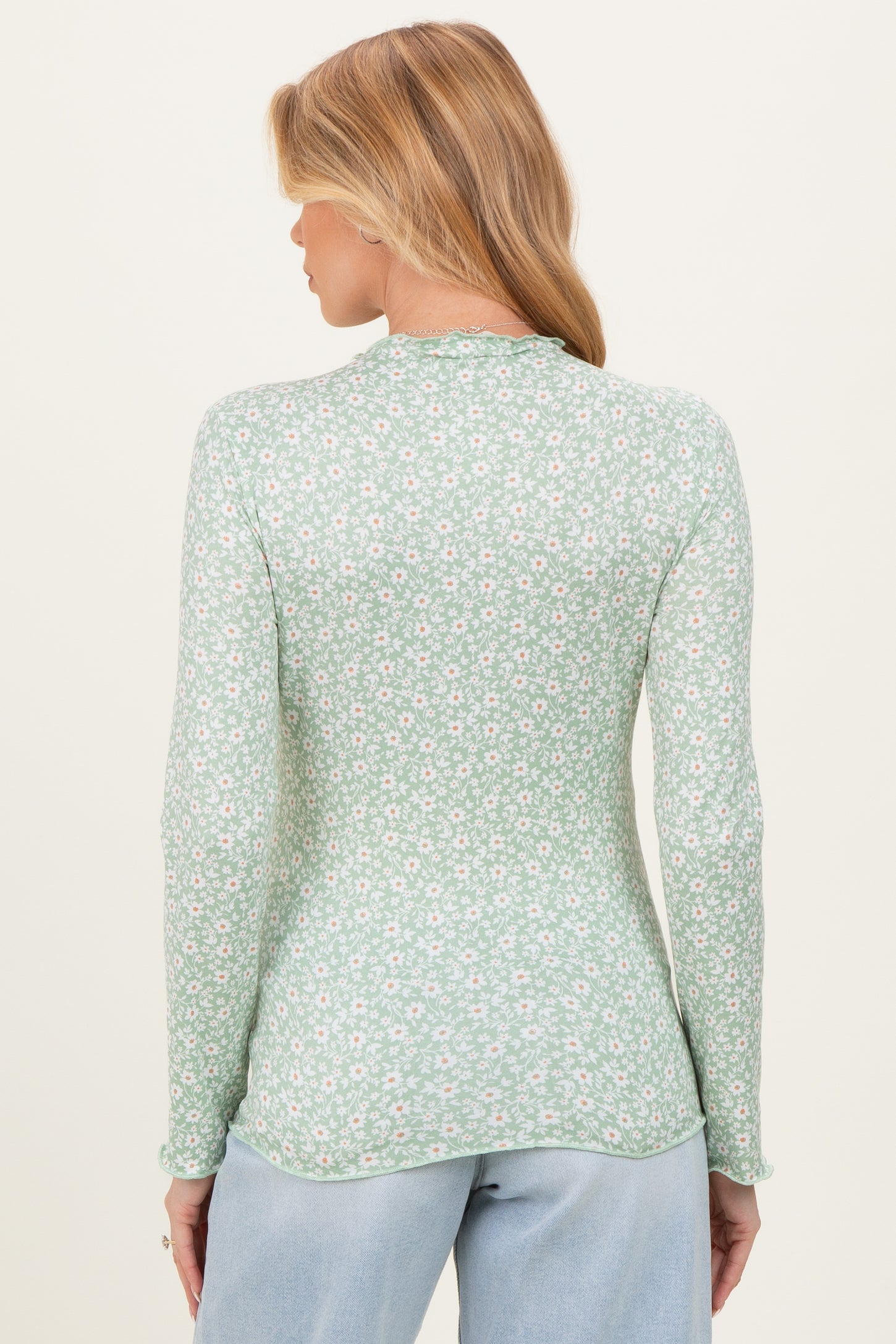 woman wearing a green floral long sleeve maternity top with a fitted style and rounded hem, showing the back view
