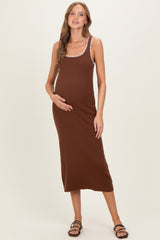 woman wearing a brown ribbed maternity dress with decorative trim and holding her baby bump