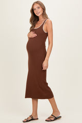 woman wearing a brown ribbed maternity dress with straps, holding her baby bump