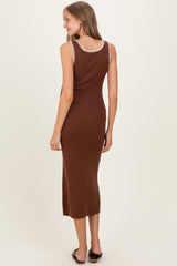 woman wearing a chocolate brown ribbed maternity dress with decorative trim on the straps, standing with her back to the camera