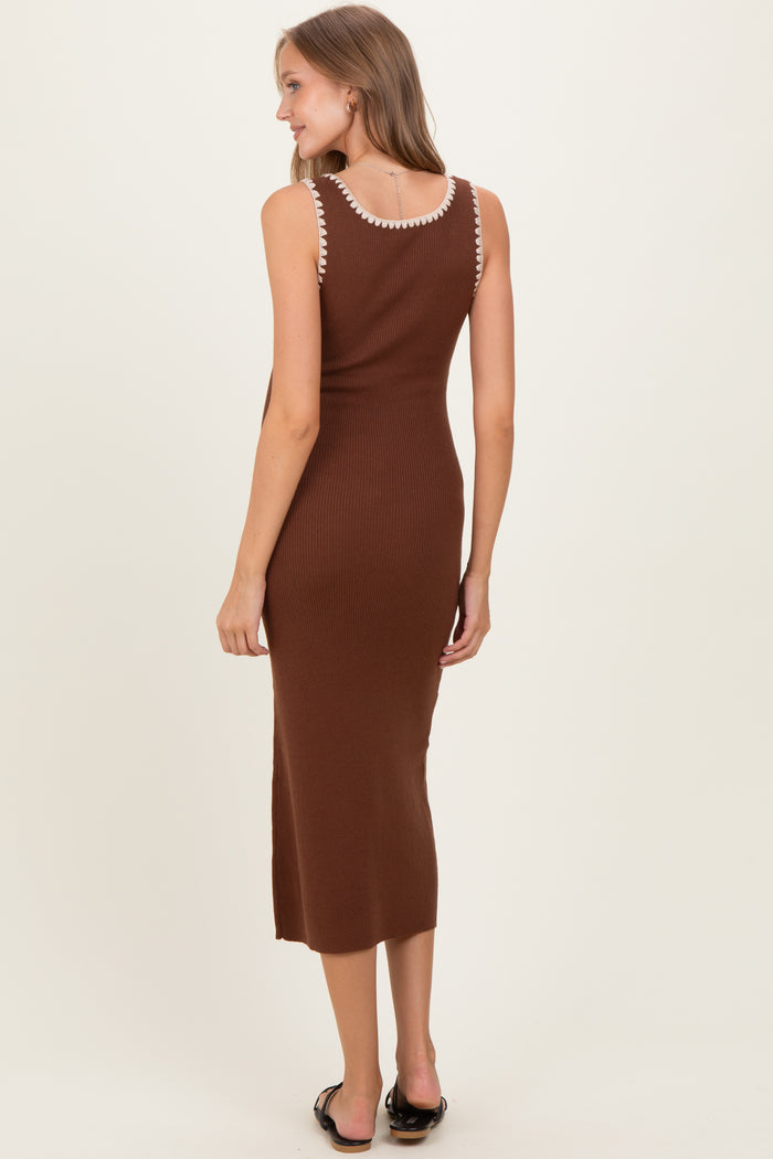 woman wearing a chocolate brown ribbed maternity dress with decorative trim on the straps, standing with her back to the camera