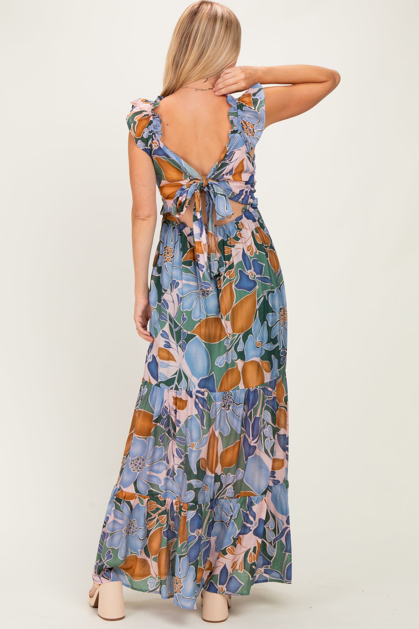 woman wearing a floral maxi dress with ruffle sleeves and an open back tied with a bow