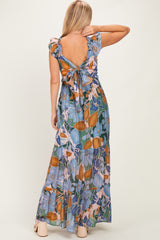 woman wearing a floral maxi dress with ruffle sleeves and an open back tied with a bow