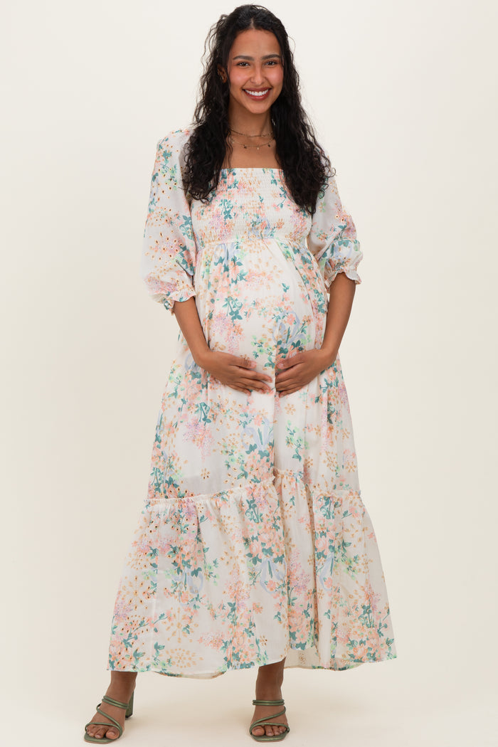 woman wearing a floral maternity maxi dress with balloon sleeves and holding her baby bump