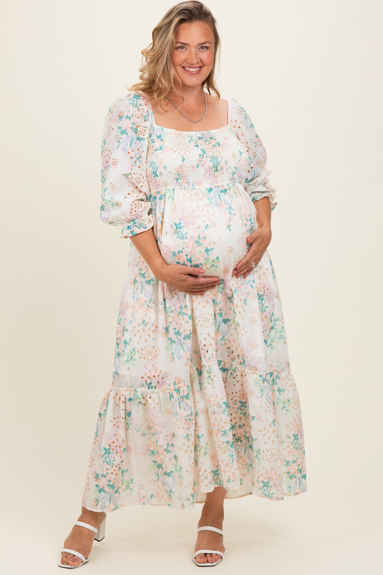woman wearing a floral print long sleeve maternity dress and holding her baby bump