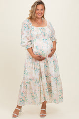woman wearing a floral print long sleeve maternity dress and holding her baby bump