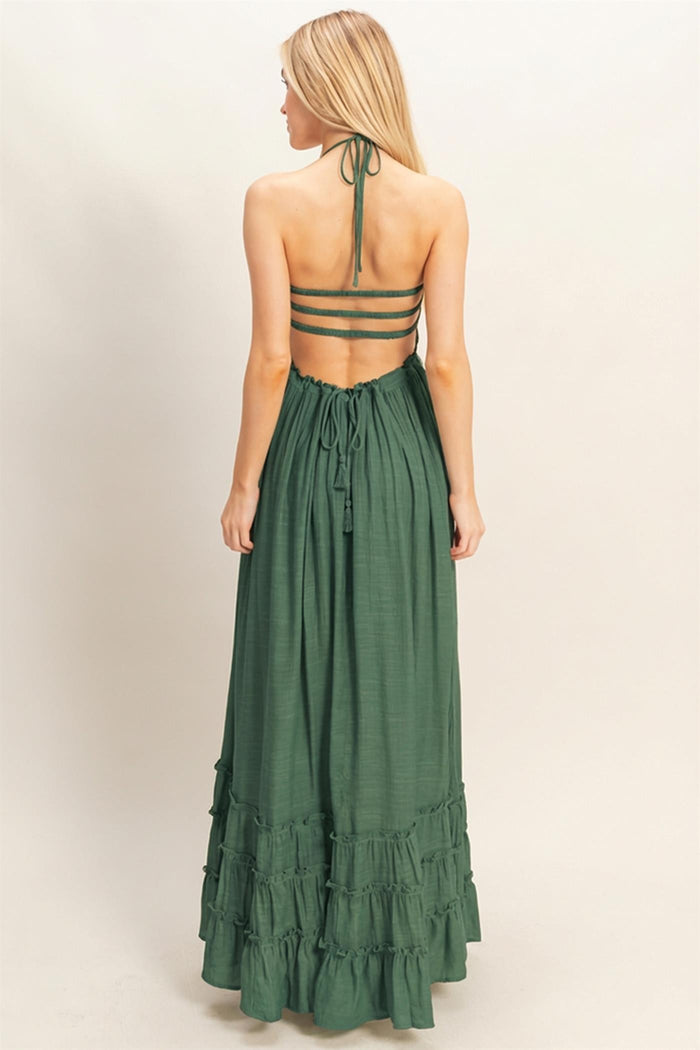woman wearing a green tiered maxi dress with a halter neck and open back design
