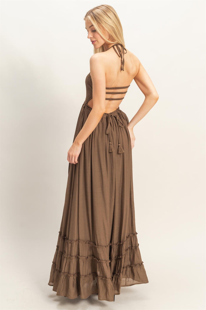 woman wearing a brown maxi dress with a strappy back and ruffle hem details