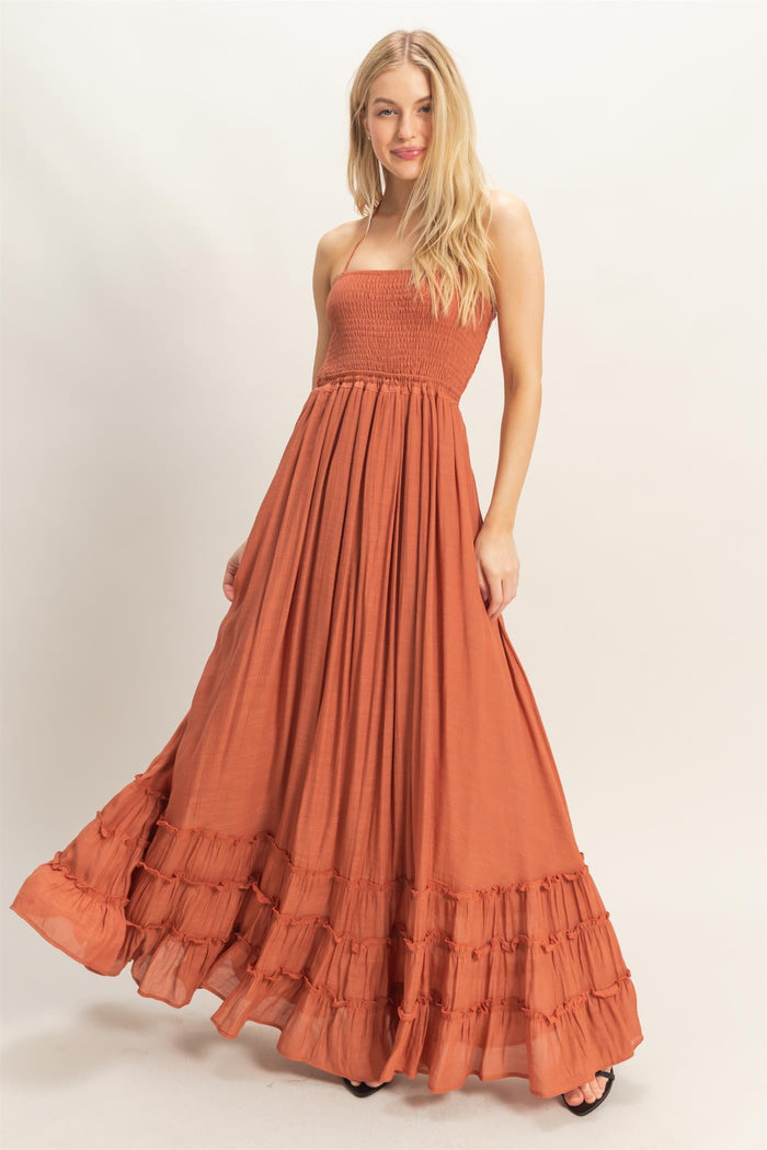 woman wearing an orange strapless maxi dress with a smocked bodice and tiered ruffle hemline