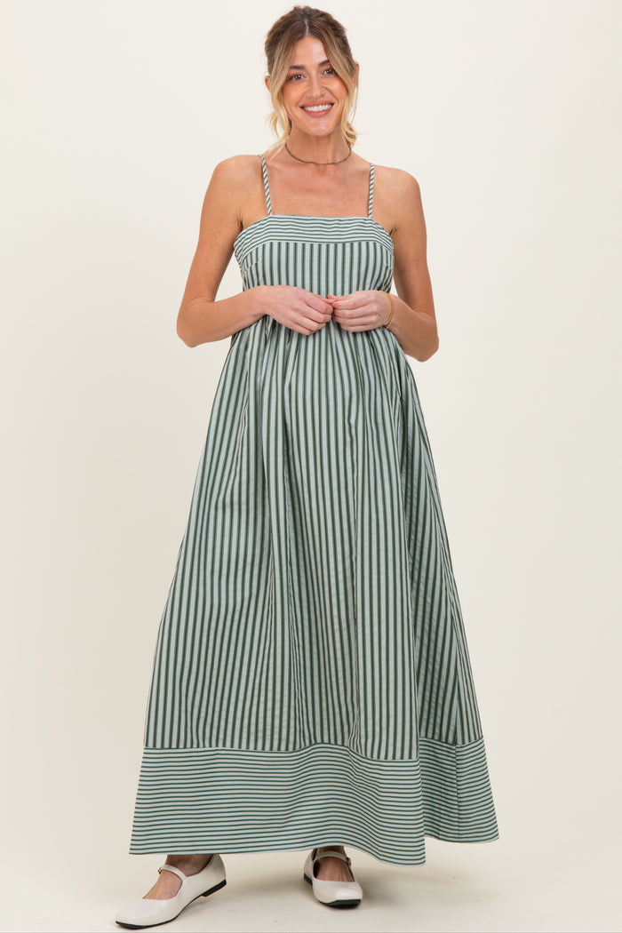 woman wearing a green and white striped maternity maxi dress with a fitted bodice and flowy skirt, baby bump visible