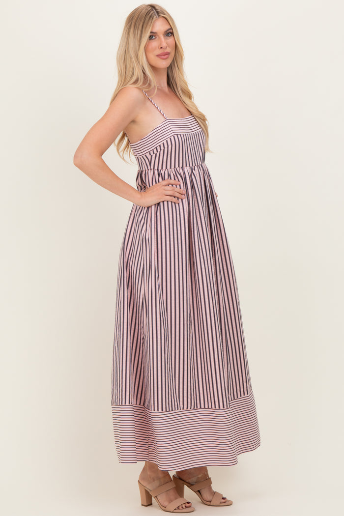 woman wearing a long striped maxi dress with a fitted bodice and flared skirt, standing in profile