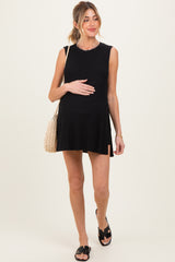 woman wearing a black ribbed sleeveless maternity dress and holding her baby bump with a straw bag over her shoulder