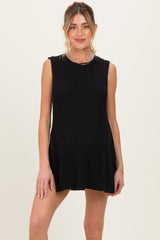 woman wearing a black sleeveless maternity dress with ribbed texture and a flared bottom, showing baby bump