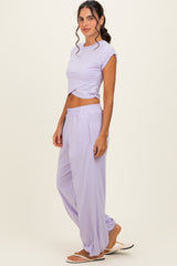 woman wearing a lavender cropped t-shirt and matching wide-leg pants, styled with flip-flops and loose waves in her hair