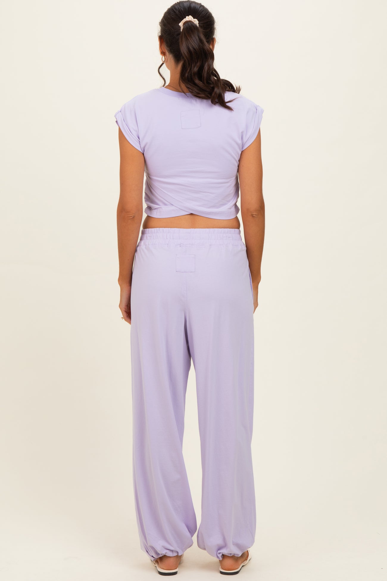 woman wearing a lavender two-piece outfit with a cropped top and wide-leg pants, seen from the back