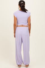 woman wearing a lavender two-piece outfit with a cropped top and wide-leg pants, seen from the back