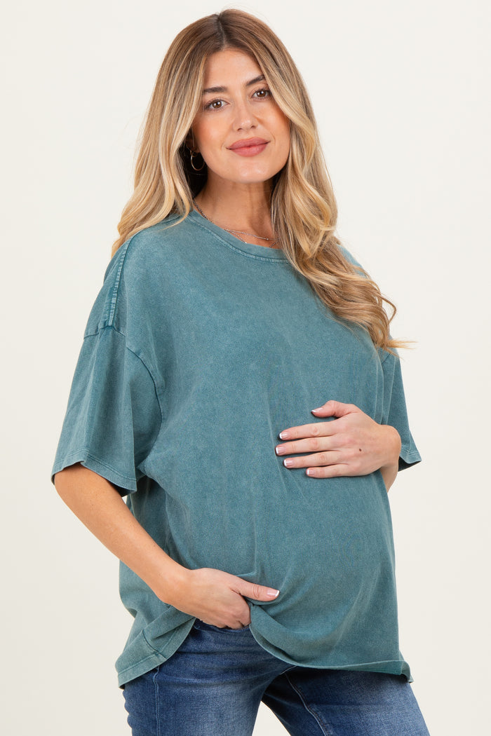 woman wearing a teal oversized maternity t-shirt and highlighting her baby bump with one hand