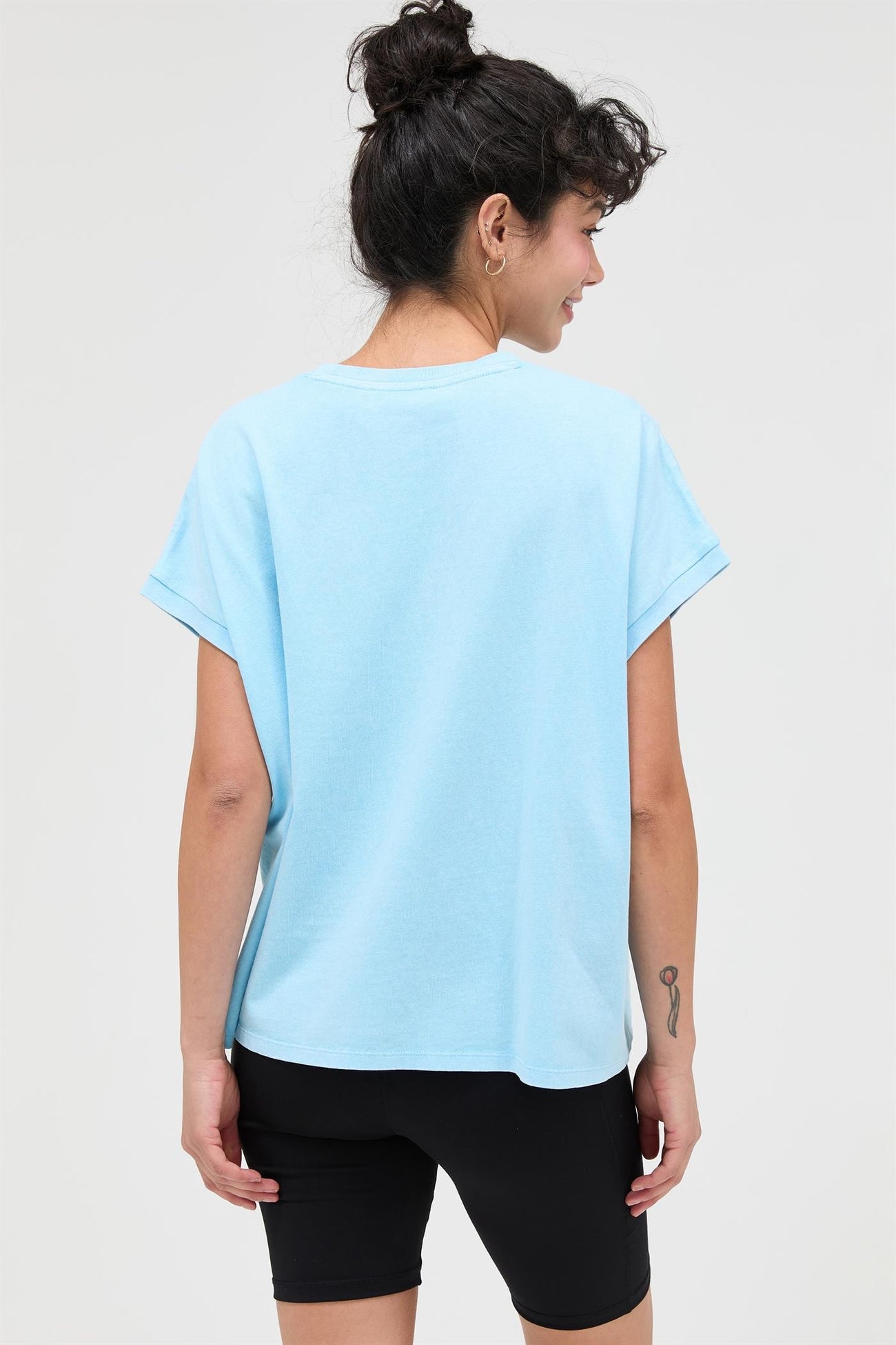 woman wearing a light blue oversized t-shirt and black bike shorts from the back