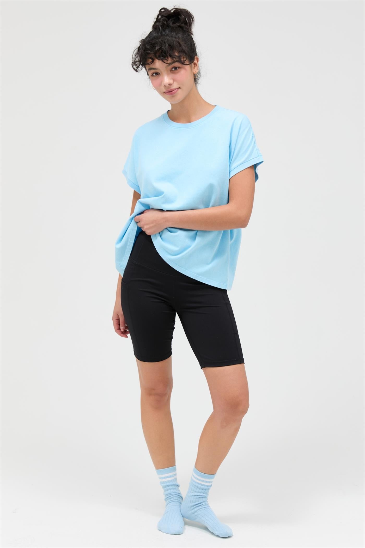 woman wearing a light blue oversized t-shirt and black biker shorts with blue socks